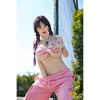 5ft 4in or 163cm curvy white female hybrid sex doll with long legs, long dark hair, large breasts, large butt, and brown eyes in a pink top and pink exercise pants.