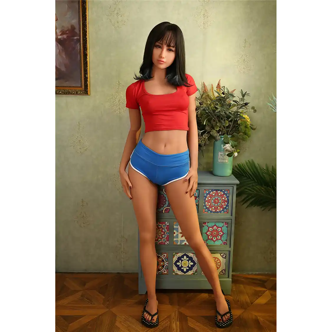 5ft 6in 166cm slim Asian TPE sex doll with shoulder length black hair, small breasts and brown eyes in a red shirt and blue shorts.